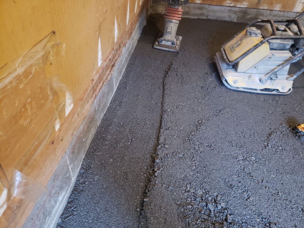 Excavated garage with compacted gravel base layer ready for new concrete.